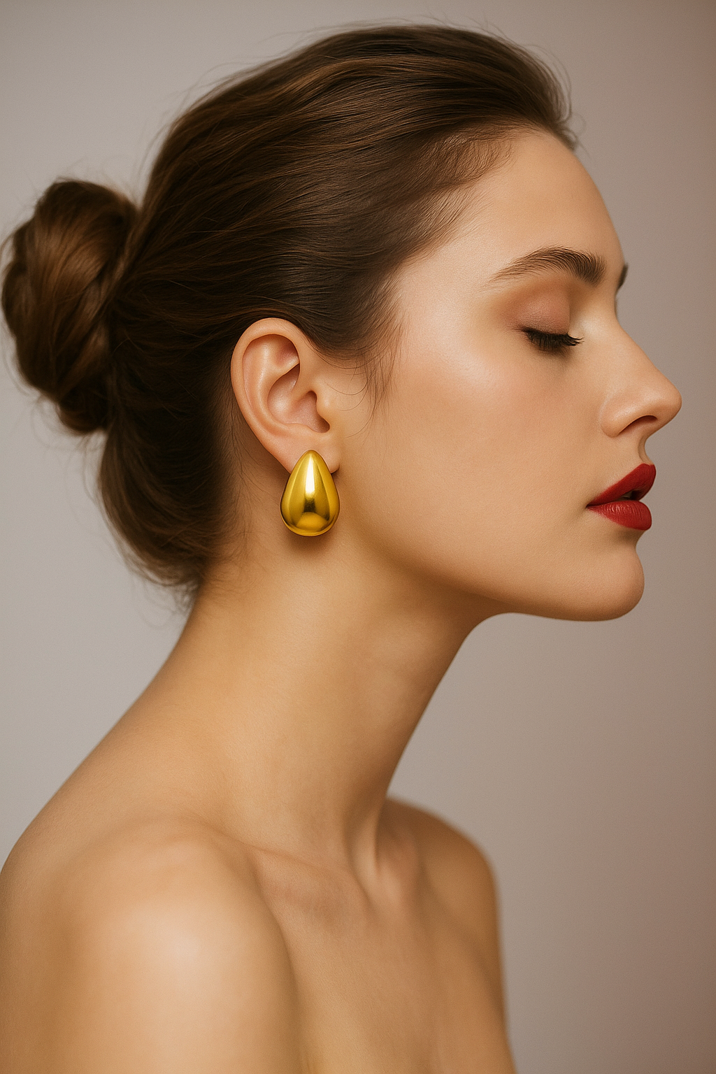 Woman wearing a gold earring against a neutral background