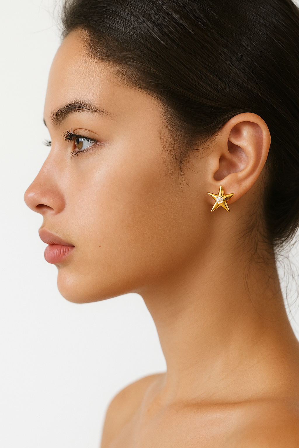 Close-up of a woman wearing gold star-shaped earrings against a white background
