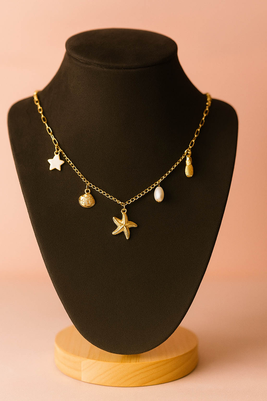 Gold necklace with starfish and beach charms- starfish,pineapple,stars , coin and pearl on a black mannequin bust against a pink background