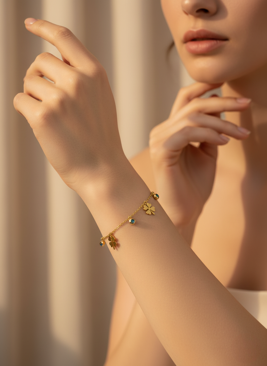Close-up of a person wearing a gold bracelet with small charms against a neutral background