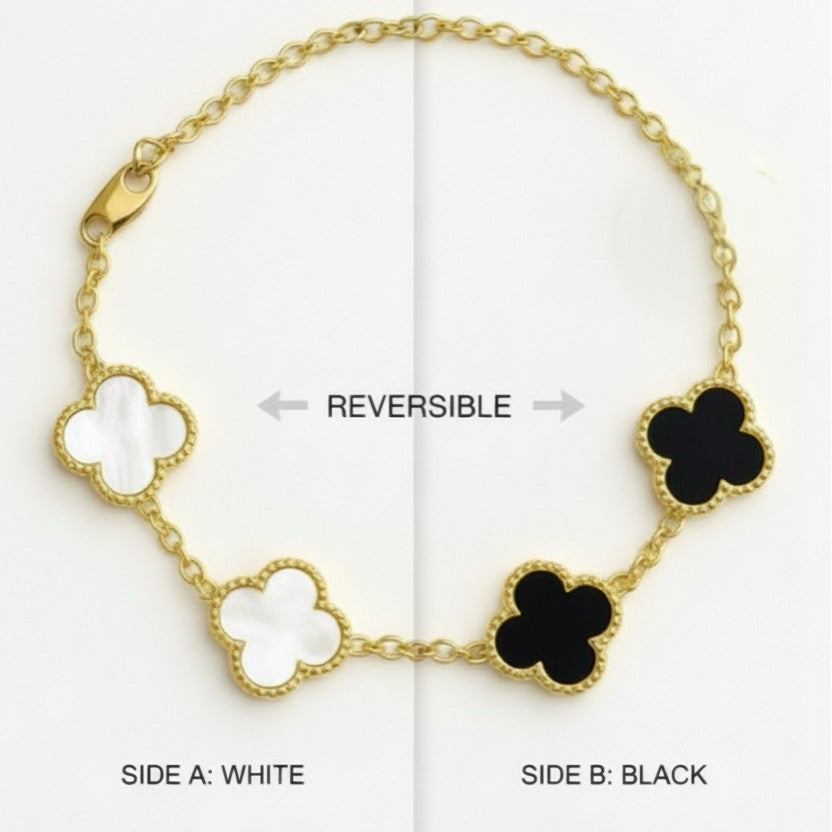 Reversible gold bracelet with white and black clover designs on a white background