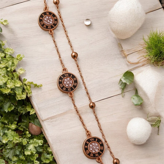 Rose gold necklace with decorative elements on a light wooden surface with plants.