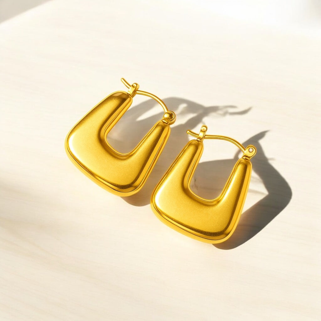 Pair of gold hoop earrings on a light beige background