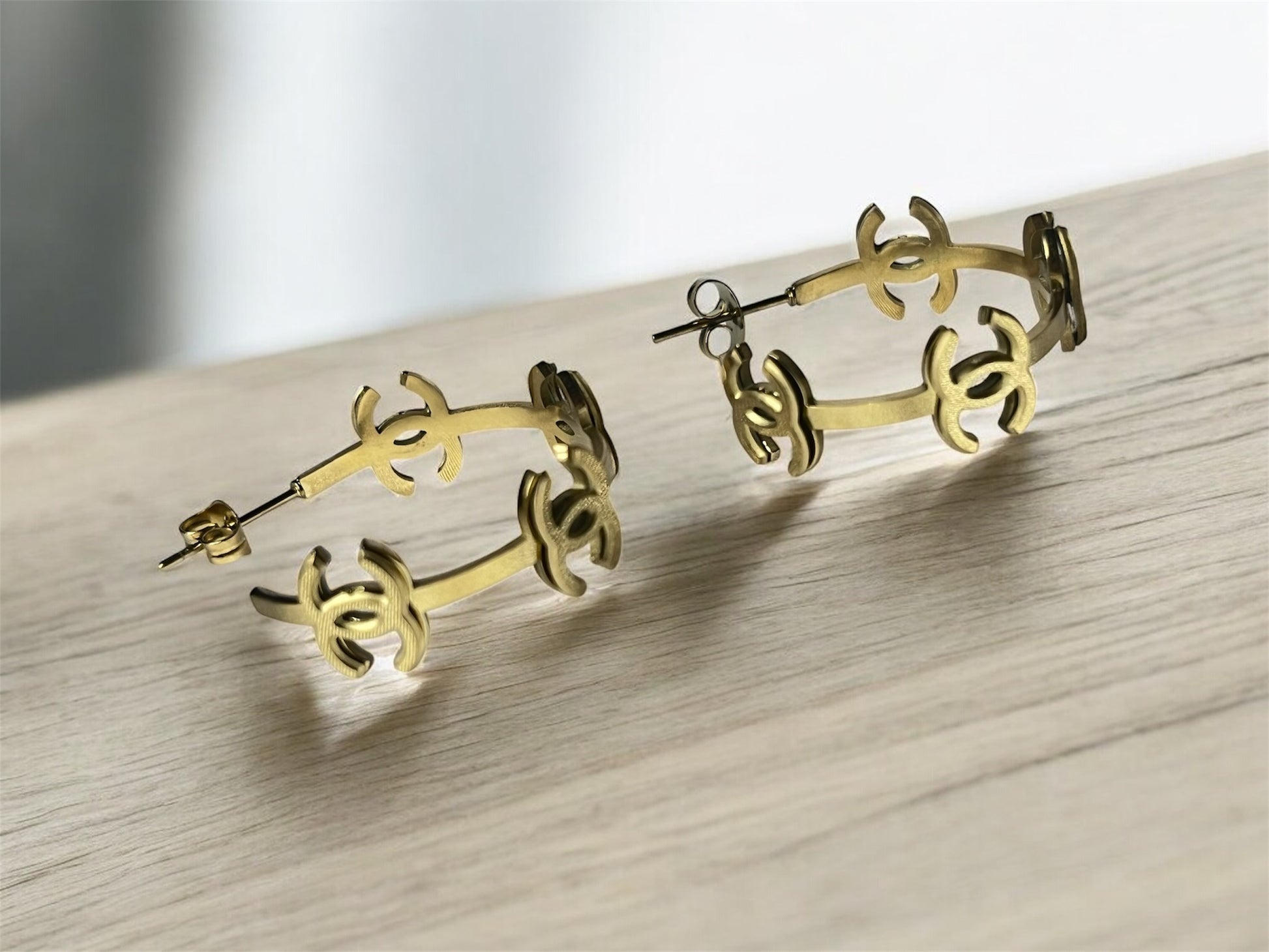 Gold hoop earrings on a light wooden surface