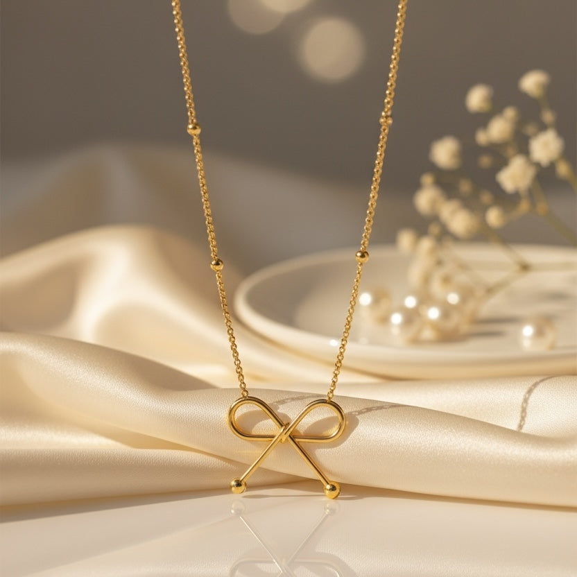 Gold necklace with a bow-shaped pendant on a beige fabric background