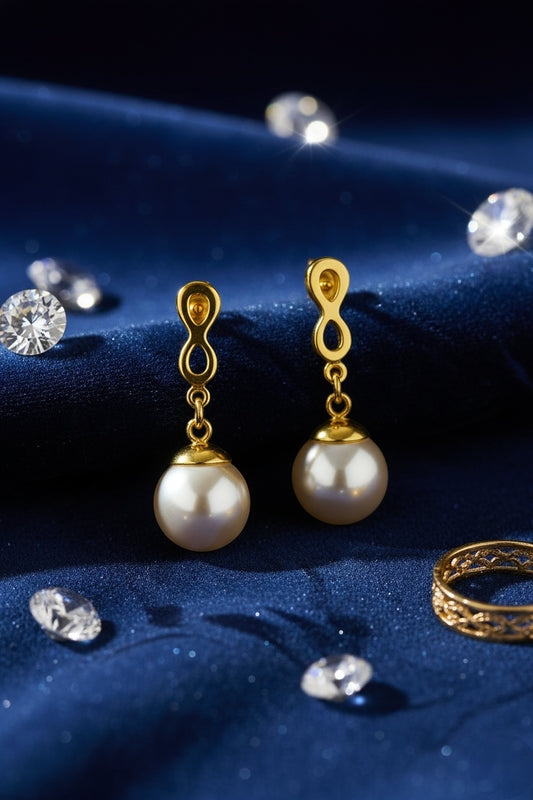 Gold earrings with pearl drops on a blue fabric background